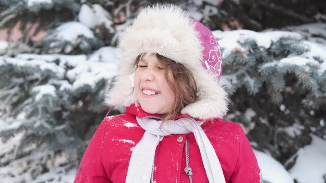 Little cute happy caucasian girl in winter hat playing in snowball