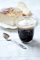 Coffee in glass cup on bright wooden background. Close up.