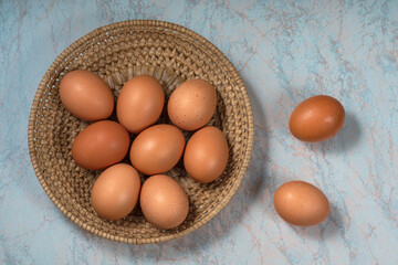several fresh chicken eggs in a straw basket on a wooden background. Healthy eating concept.