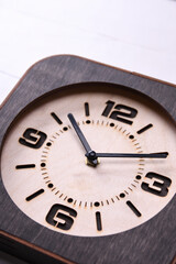 Fototapeta na wymiar Wooden clock made in hand on wooden background. Close-up. Place for text.