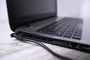 Laptop, computer is charging from a 220-volt outlet on a desk near the wall. Energy, accumulation. Mockup