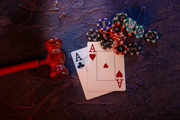 Law and rules for online casino concept, judge gavel with aces and playing chips on a grey...