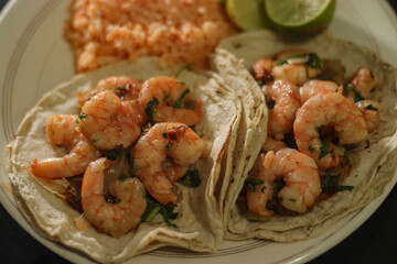 Close up Agillo shrimp tacos with red rice soup and lemons.