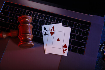 Law and rules for online casino concept, judge gavel with aces on keyboard.