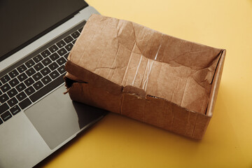 Spoiled paper box and laptop. Online shopping and delivery concept. Shipment accident.