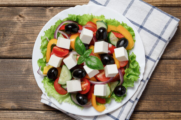 Greek salad with cheese and fresh vegetables on wooden background.