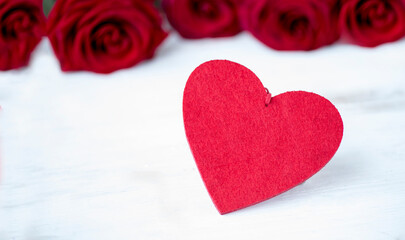 Fototapeta premium Festive frame for Valentine's Day. Red heart on a background of scarlet roses.