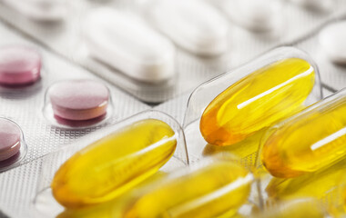 A bunch of medical pills in yellow and other colors. Tablets in plastic packaging.