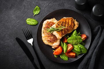 Meat steaks with fresh salad. Top view image at black table.