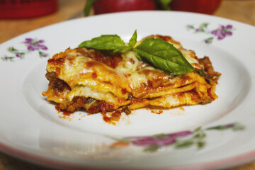 Traditional italian  dish:  lasagna bolognese garnished with fresh basilic. 