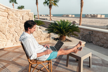 freelancer with a laptop in his hands works on vacation