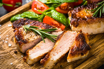 Meat steaks with fresh salad served at wooden board. Close up