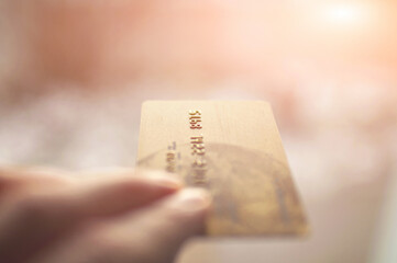 bank card of gold color in hands on a background of sunlight