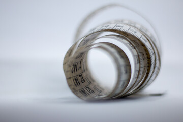 Close up of a two meter long measuring tape. The tape is rolled up in a way you can look through.