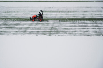 Fototapeta na wymiar Removing snow with tractor from the soccer pitch.