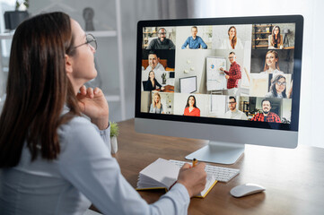 Group of diverse multiracial people on the laptop screen, a young woman is talking with colleagues,...