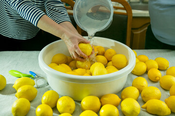 The process of making limoncello lemon liqueur at home. A man and a woman wash lemons in a...
