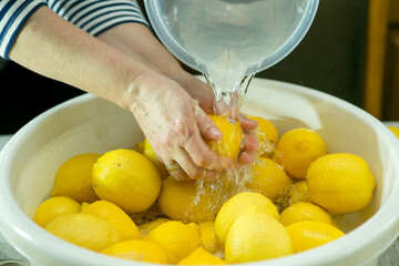 The process of making limoncello lemon liqueur at home. A man and a woman wash lemons in a...