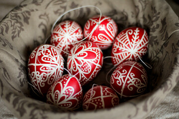 eight decorated easter eggs in Hungarian style in red and white in a basket like a nest