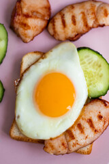  sandwich with egg, cucumber and bacon on a pink plate. healthy breakfast for one. beautiful food setting. High quality photo