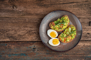 Vegetarian appetizer with avocado sandwiches and sliced boiled eggs on a wooden background. Top view, with space to copy. The concept of proper nutrition.