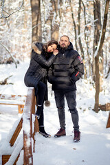 Man and woman in love holding hands on a bridge. Snowy winter background.