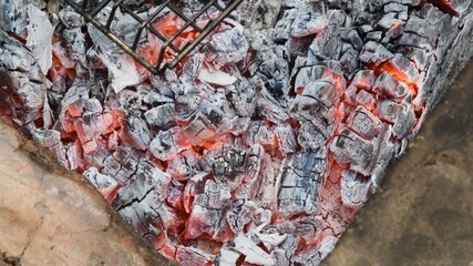 Natural wooden coals burning for barbecue, smoldering and glowing in grill, for preparing grilled food. Blurred background of smolder charcoals. Hot embers texture
