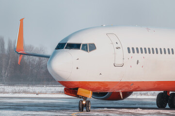 Obraz premium Modern passenger airplane on the apron of airport during taxiing. Winter taxi on apron. Snow blizzard. Airport in snow.