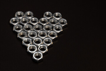 Heart shape made of hex bolts on dark grey background. Creative love concept