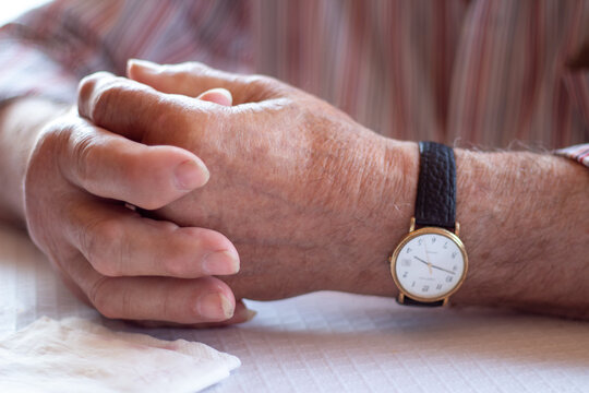 Manos de se&ntilde;or mayor  con artrosis y reloj anal&oacute;gico con correa de cuero