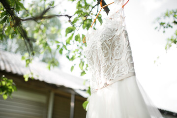 The wedding dress hangs on the tree.
