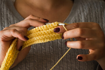 The woman knits woolen clothes. Knitting needles.