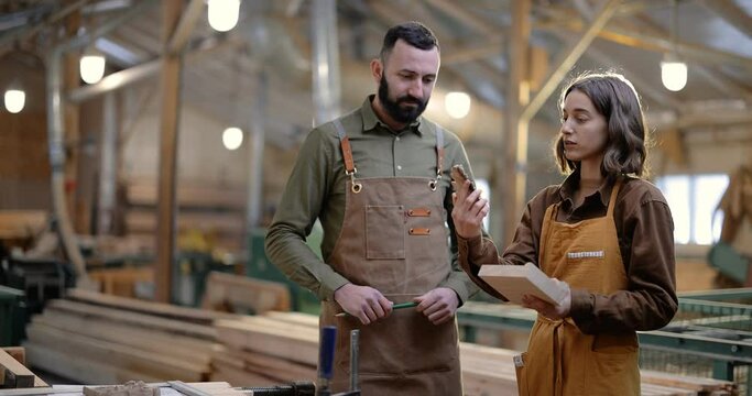 Two carpentry workers discuss woodwork at the manufacturing. Designing woodwork or supervising production. Colleagues at the joinery factory