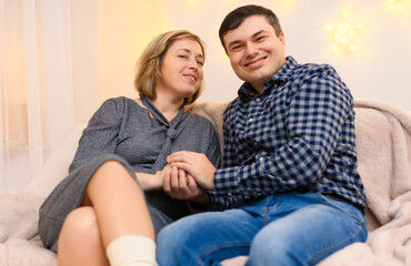 portrait of adult couple sitting on a sofa at home