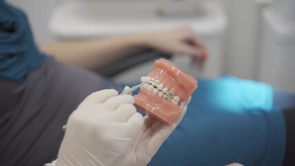 Dentist holding Dental teeth model using explorer to explain invisible retainer or braces procedure or removable transparent plastic aligners. Modern dental technology. Close up on orthodontist 
