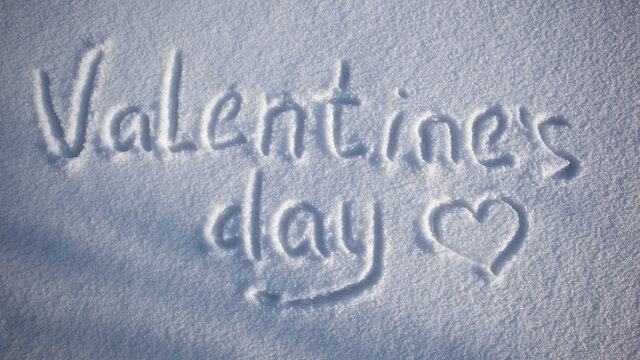 Valentine's Day lettering on the snow. Valentine's Day. The 14th of February. Valentine's day mood concept. Drawn heart in the snow. The inscription on the snow.