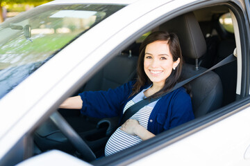 Beautiful pregnant woman with her hands on the steering wheel