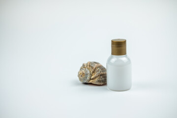 Photo of a shampoo bottle near a shell and a white background