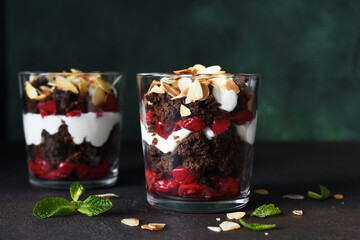 Dessert black forest with cherries in a glass on a dark green background. Traditional German dessert. Horizontal focus.
