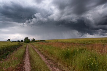 Spring summer thunderstorm rural road among fields
