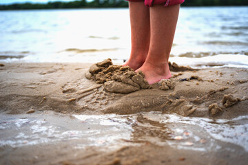 children's feet dig sand on the beach near the water