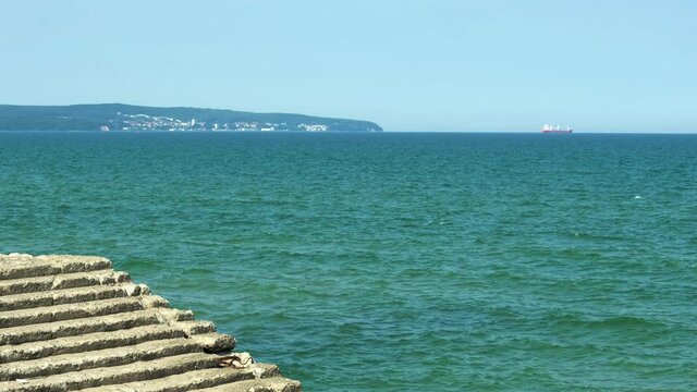 Colorful blue teal water waves of the Baltic Sea on a summer day at the beach with a stair in the foreground