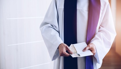 Catholic priest holding envelope with money during pastoral visit called kolenda in Poland, church...