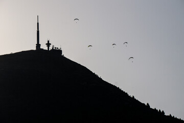 Silhouette in backlight of the Puy de Dome Volcano with paragliders and the meteorological observatory on top. It is the most famous volcano of the Chaine des Puys volcanoes range in Auvergne, France