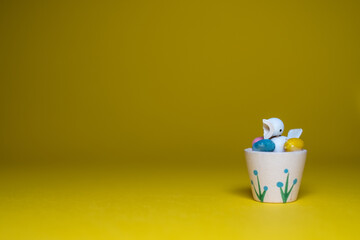 Happy Easter greeting card background with empty copy space. Cute little chick with colorful easter egs on yellow background.