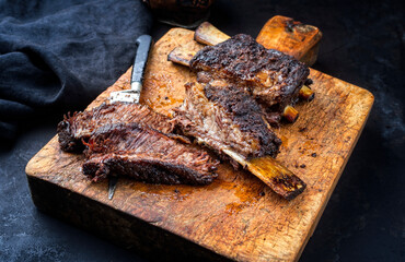 Traditional barbecue burnt chuck beef ribs marinated with spicy rub served as close-up on a rustic old wooden cutting board