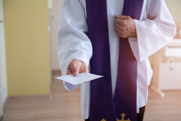 Catholic priest holding envelope with money during pastoral visit called kolenda in Poland, church...