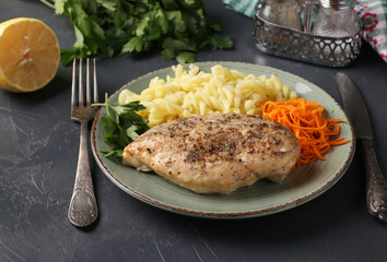 Baked chicken fillet, pasta and fresh carrots - a delicious and healthy breakfast. Close-up