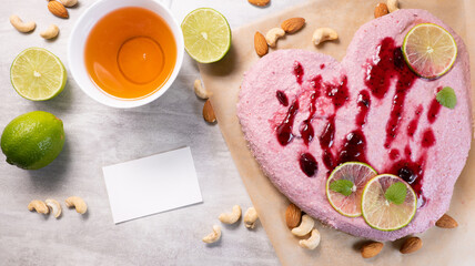 Top view of heart shaped vegan raw cake with strawberry and cashew nuts on the table