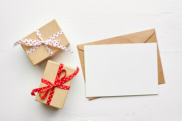 Greeting card mockup and gift boxes on white wooden background